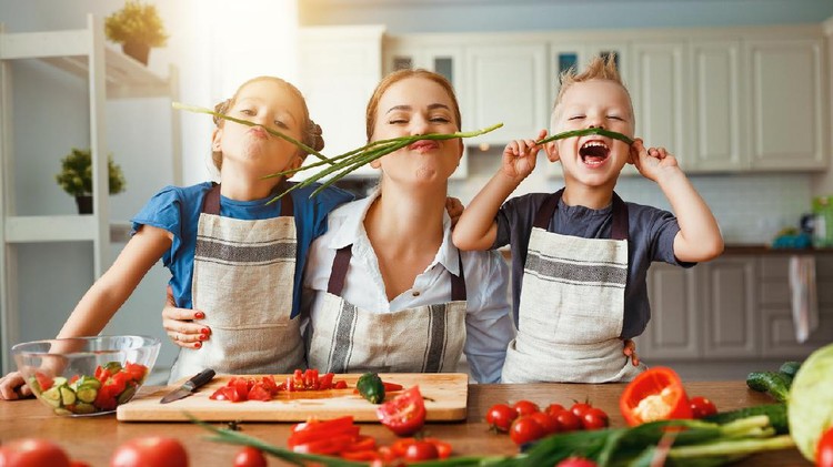 mother with children preparing vegetable salad at home