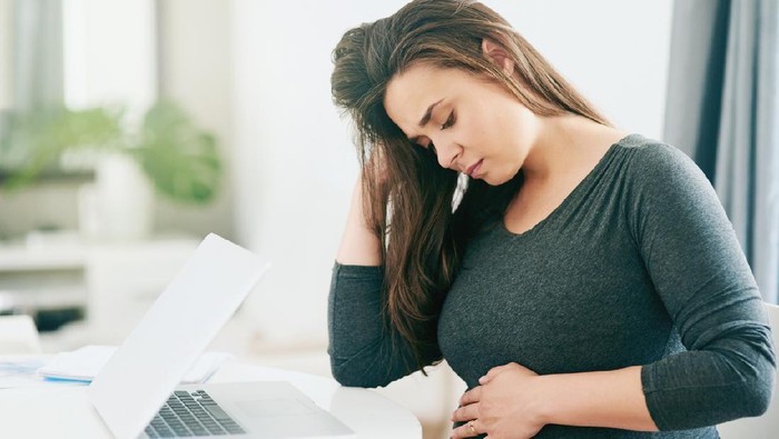 Shot of a young pregnant woman feeling unwell while working from home