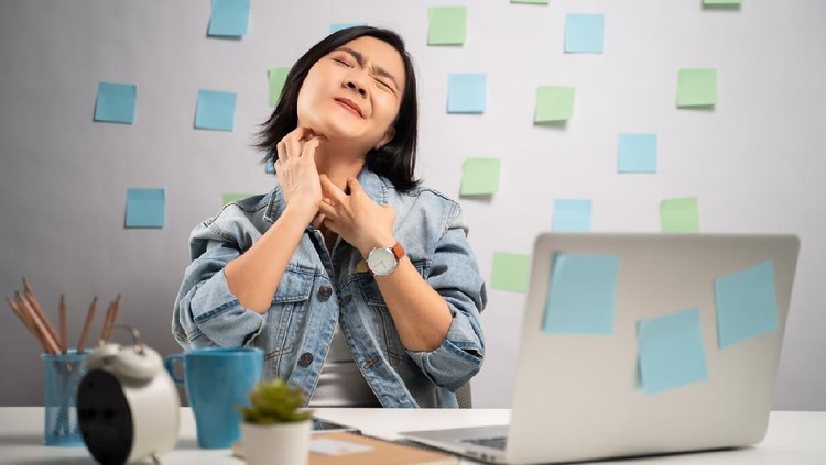 Alergi Bekerja Asian woman working on a laptop and scratching her skin sitting at home office. WFH. Work from home. Prevention Coronavirus COVID-19 concept.