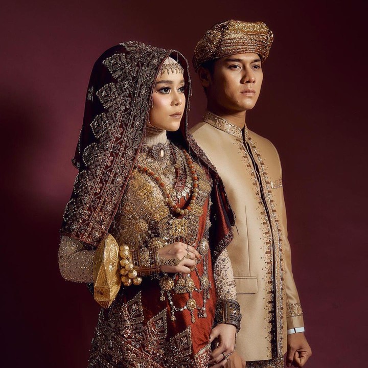 <p>Konsep foto dengan adat Minangkabau dipilih oleh pasangan Rizky Billar dan Lesty Kejora. Mereka tampil serasi dalam balutan baju adat bernuansa keemasan. (Foto: Instagram: @aldiphoto)</p>