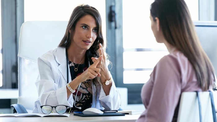 Shot of serious young gynecologist giving guidelines to his pregnant patient in the clinic.