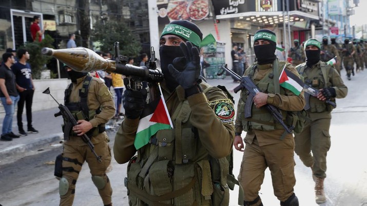 Masked militants from the Izzedine al-Qassam Brigades, a military wing of Hamas, march with their rifles a long the streets of Nusseirat refugee camp, central Gaza Strip, Friday, May 28, 2021. Arabic on the headband reads 