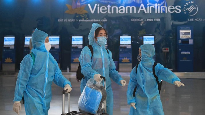 People in full protective gear walk through Noi Bai airport in Hanoi, Vietnam, Friday, Feb. 12, 2020. A fresh COVID-19 outbreak in Vietnam has slowed down business and travel during the popular lunar new year festival. (AP Photo/Hau Dinh)