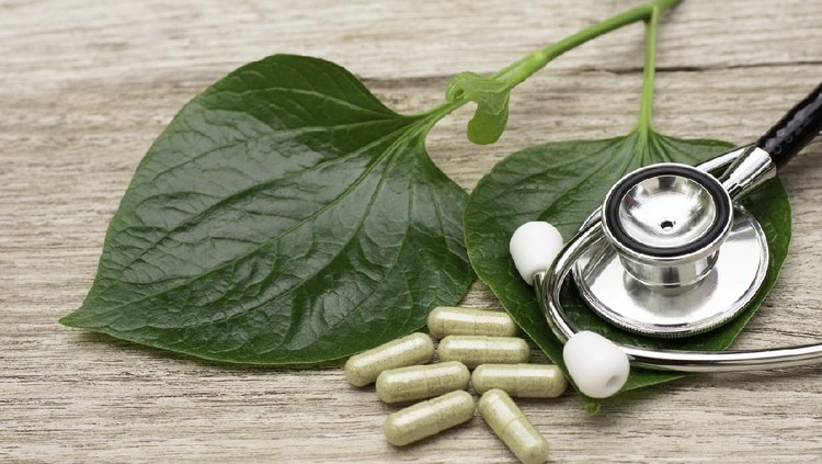 daun sirih Betel Essential oil in bottle and green leaf on wooden table. Betel is a vine that has the heart shaped leaves.