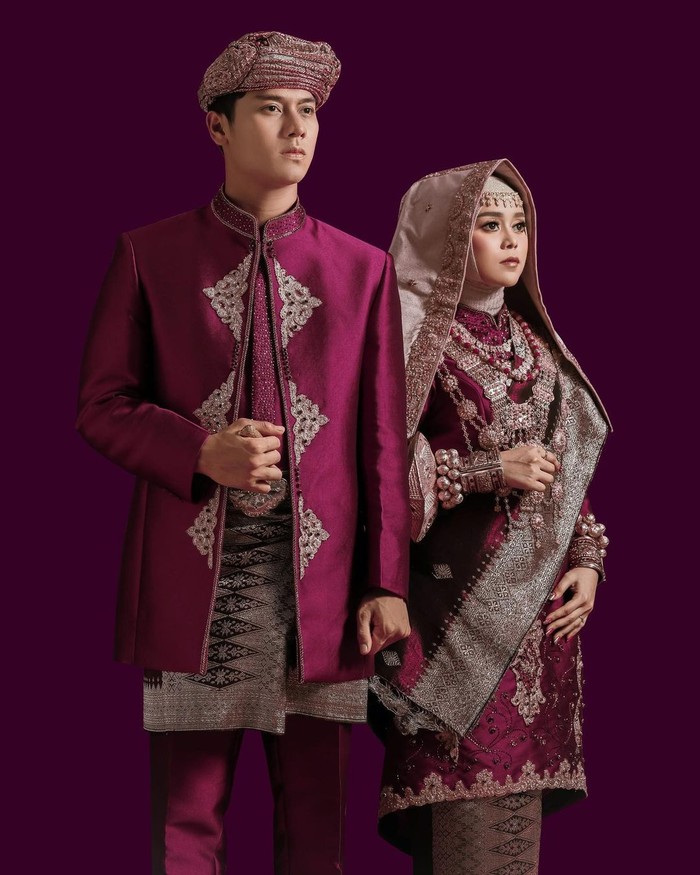 Lesti terlihat sangat anggun dengan pakaian minang nuansa ungu yang dipadukan dengan tengkuluk talakuang berwarna emas. Begitu pula dengan Billar yang nampak memesona dengan jas nuansa ungu dan kain songket yang senada. (Foto: Instagram.com/aldiphoto)