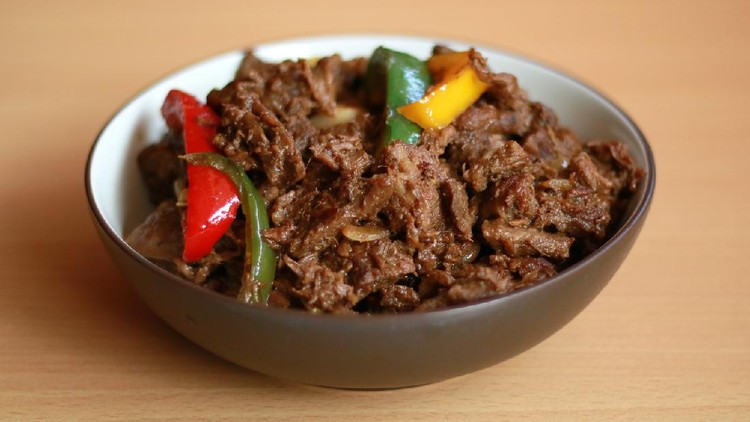 Black pepper beef in bowl with wood background.