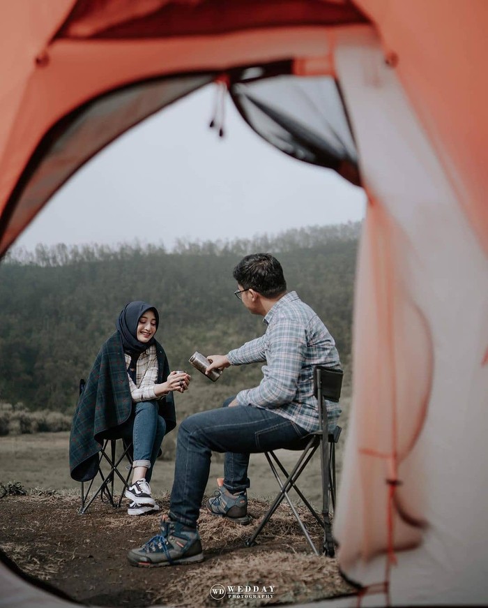 Pasangan pecinta alam wajib banget sih punya foto pre wedding di gunung, danau, hutan atau tempat lainnya. Sudut pandang dari tenda serta adegan menuangkan minuman ini terlihat sangat menarik. (Foto: instagram.com/preweddingkeren/)