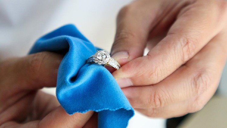 Jeweller hand polishing and cleaning jewelry diamond ring with micro fiber fabric