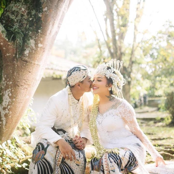 <p>Pernikahan Alfath Fathier dan Nadia Christina mengusung tema adat Sunda seperti yang terlihat dari busana mereka. Alfath tampak mencium sang istri dengan penuh cinta. (Foto: Instagram: @__nadiachristina)</p>