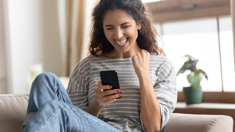 Overjoyed young pretty woman making yes gesture, reading unbelievable news on smartphone. Excited millennial attractive lady looking at mobile screen, receive online lottery win notification.