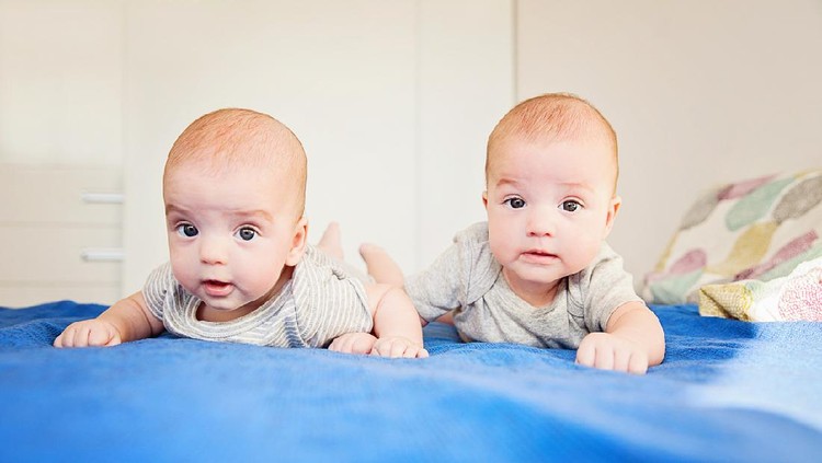 Twin baby boys on lying down on bed