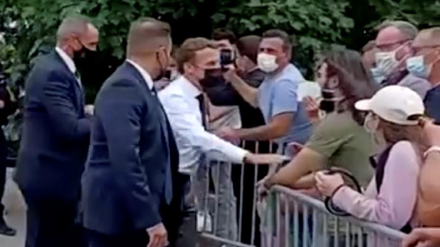 French President Emmanuel Macron speaks with a member of the public before he was slapped during a visit in Tain-L'Hermitage, France, in this still image taken from video on June 8, 2021. BFMTV/ReutersTV via REUTERS ATTENTION EDITORS - THIS VIDEO WAS PROVIDED BY A THIRD PARTY. THIS IMAGE WAS PROCESSED BY REUTERS TO ENHANCE QUALITY. UNPROCESSED VERSION OF THE VIDEO WAS PROVIDED SEPARATELY. NO RESALES. NO ARCHIVE. FRANCE OUT. NO COMMERCIAL OR EDITORIAL SALES IN FRANCE