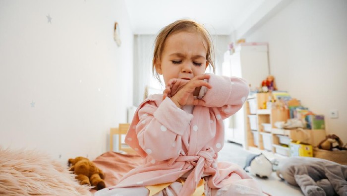 Sick 3 years old girl coughing in bed