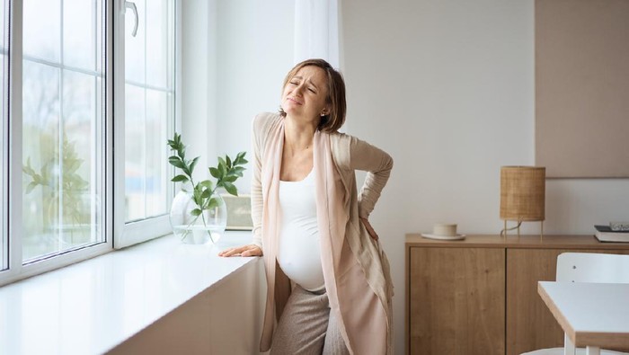 Healthcare, treatment. Young pregnant woman feeling sudden pain in her back. Future mom suffering from backpain. High quality photo
