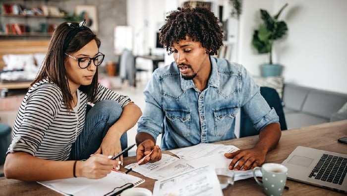 Modern married multi-ethnic young couple calculating financial bills at home