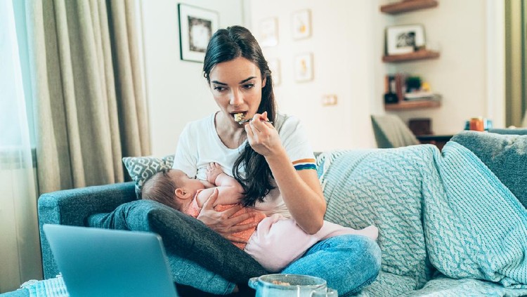 Young Mom Breastfeeding Baby While Working Remotely On Laptop At Home and eating