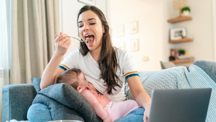 Young Mom Breastfeeding Baby While Working Remotely On Laptop At Home and eating