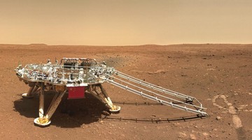 In this image released by the China National Space Administration (CNSA) on Friday, June 11, 2021, the landing platform with a Chinese national flag and outlines of the mascots for the 2022 Beijing Winter Olympics and Paralympics on Mars is seen from the rover Zhurong. China on Friday released a series of photos taken by its Zhurong rover on the surface of Mars, including one of the rover itself taken by a remote camera. (CNSA via AP)