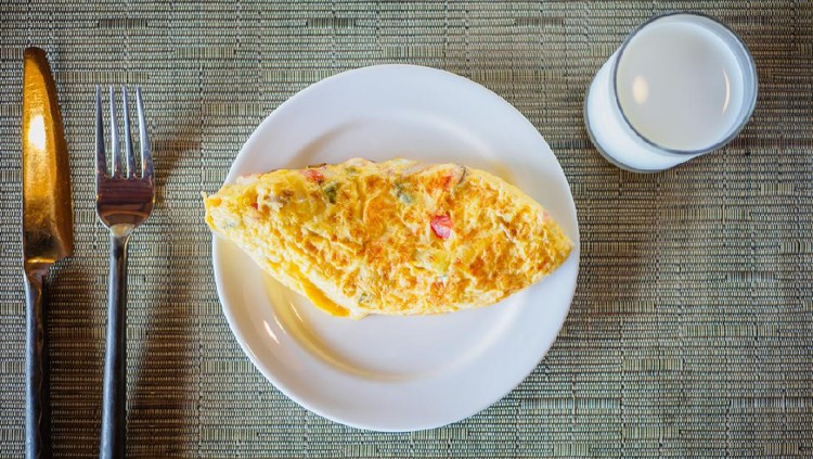 Top view a plate of scrambled eggs and a glass of milk for breakfast meal, selective focus.