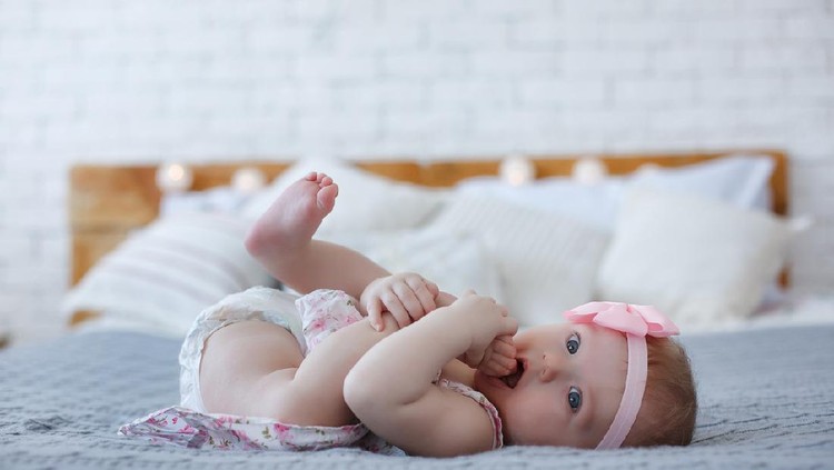 The newborn was wrapped in a green cloth and was placed on a soft rubber mat with a blurred background.