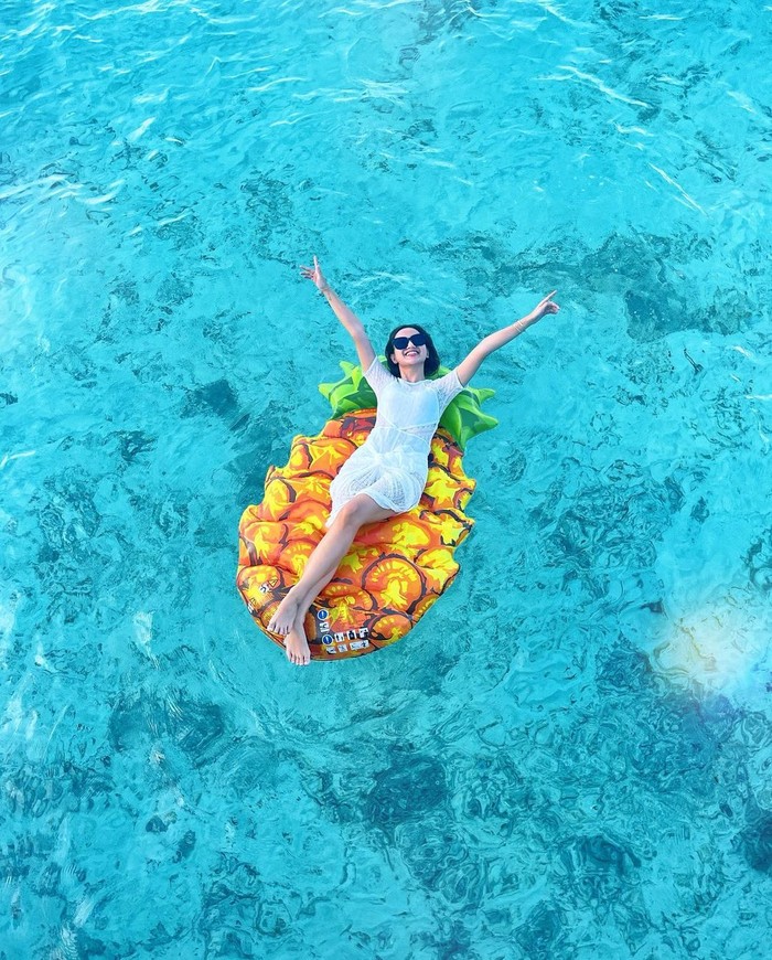 Saat honeymoonnya kemarin, Nanda membagikan potretnya yang tengah berjemur dengan float ban berbentuk nanas. Pemandangan jernih air laut terlihat kontras dengan float ban yang digunakan. (Instagram.com/nandaarsynt)