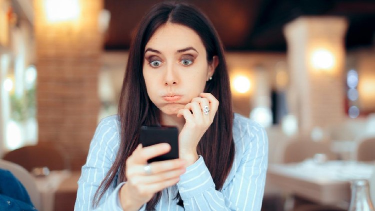 Stressed young woman checking her phone in a restaurant