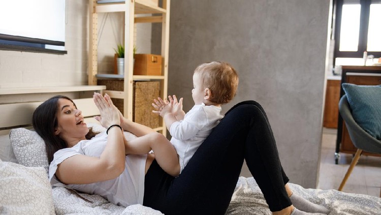 anak main Mother playing clapping game with her baby boy on bed