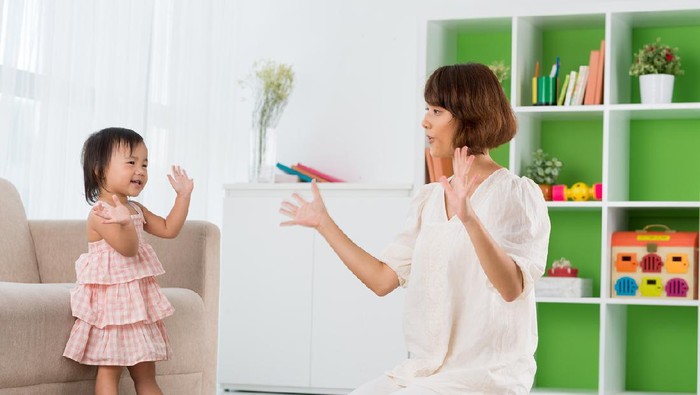 Mother playing clapping game with her baby boy on bed