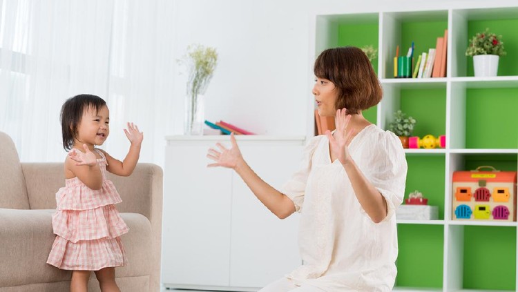 Mother playing clapping game with her baby boy on bed