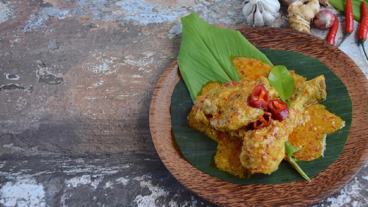 Ayam Kalio Ayam Kalio Padang or wet saucy chicken rendang. Served on banana leaf and turmeric leaf garnish with chili and kaffir lime leaf