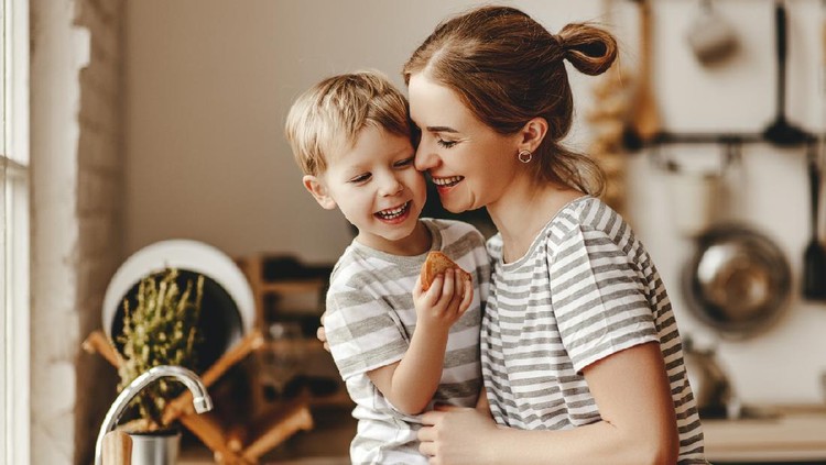 preparation of a family breakfast. mother and child son cut bread and eat cookies with milk in morning