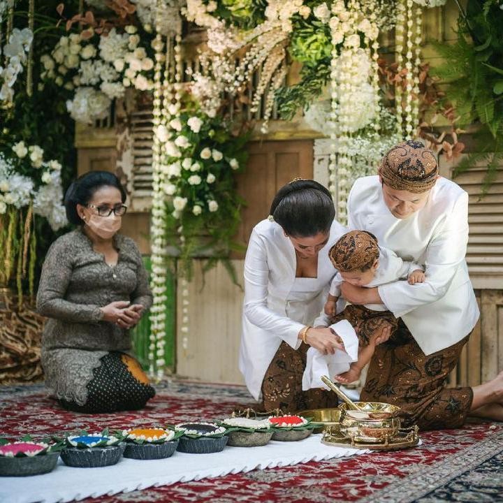 <p>Titi dan keluarga kompak mengenakan pakaian adat Jawa warna putih dengan kain batik cokelat, nih. Sementara itu, sang suami dan Bhaskara mengenakan blangkon dengan warna senada. Kehadiran sang suami pun curi perhatian netizen. (Foto: Instagram: @titiradjopadmaja)</p>