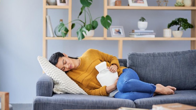 Shot of a young woman suffering with stomach cramps at home