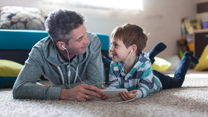 Smiling boy listenig music with his father
