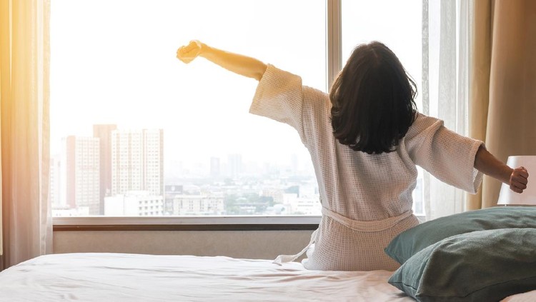 Simple city lifestyle happy woman waking up in the morning taking some rest relaxing in luxury comfy city hotel room