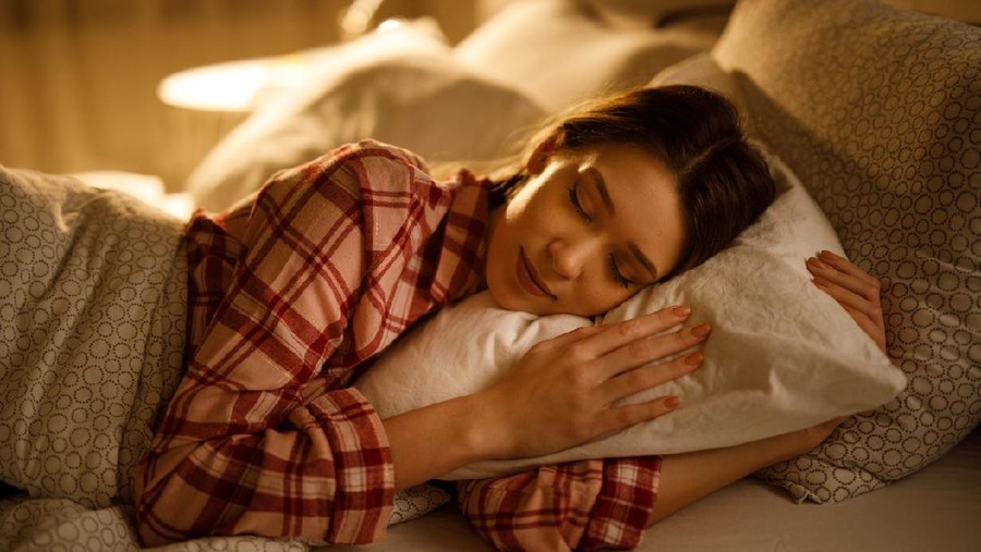 Woman sleeping in bed hugging soft white pillow