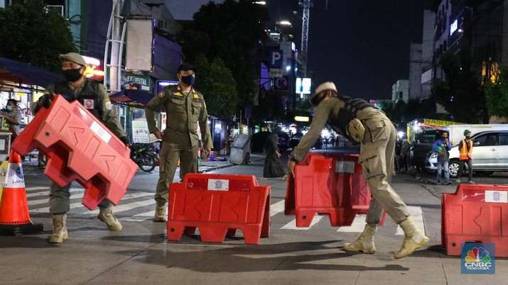 Petugas Kepolisian dan Satpol PP menutup jalan saat penerapan pembatasan mobilitas masyarakat di kawasan kuliner Jalan Sabang, Jakarta, Senin (21/6/2021). (CNBC Indonesia/ Andrean Kristianto)