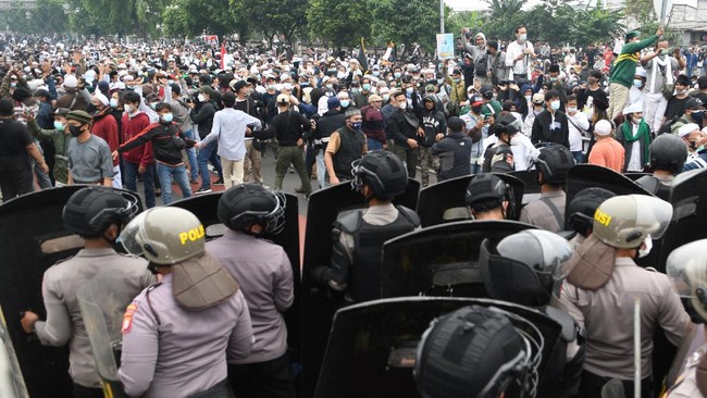 Bentrok polisi dan massa pendukung Rizieq, menurut Kapolres Metro Jakarta Timur Kombes Erwin Kurniawan, dipicu ulah massa yang menceburkan kendaraan ke sungai.