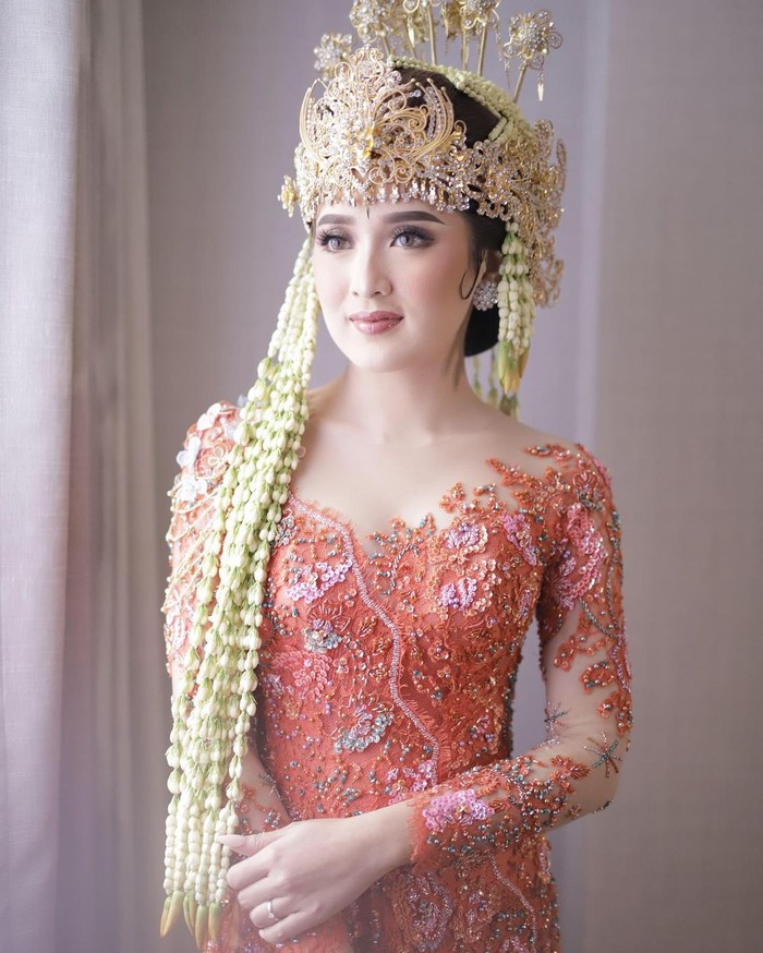 Berbeda dengan pengantin kebanyakan yang memilih putih, Rosiana Dewi memilih memadupadankan Siger Sunda berwarna gold dengan kebaya berwarna oranye di hari akadnya. Dengan padanan ini, Rosiana tampil sangat fresh! (Instagram/rsn.dw)