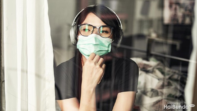 ilustrasi isoman/isolasi mandiri saat terinfeksi covid-19 Portrait of young woman in the her apartment wearing face protective mask to prevent Coronavirus
