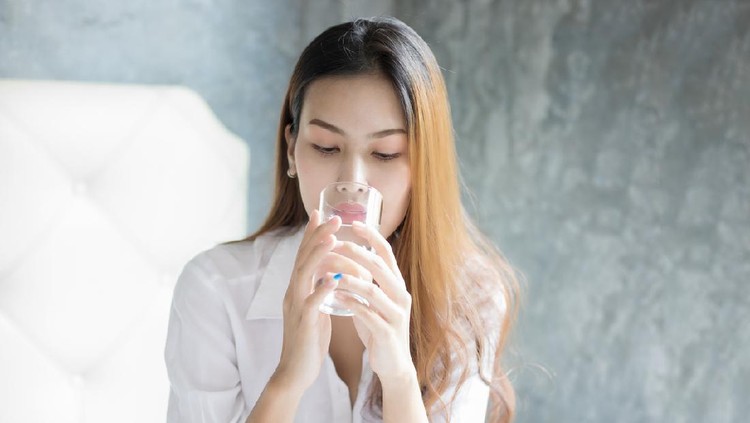 Ilustrasi Minum Air Asian Young woman drinking glass of water in bed at morning