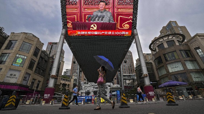 People walk past a large video screen outside a shopping mall showing Chinese President Xi Jinping speaking during an event to commemorate the 100th anniversary of China's Communist Party at Tiananmen Square in Beijing, Thursday, July 1, 2021. China's ruling Communist Party is marking the 100th anniversary of its founding with speeches and grand displays intended to showcase economic progress and social stability to justify its iron grip on political power. (AP Photo/Andy Wong)