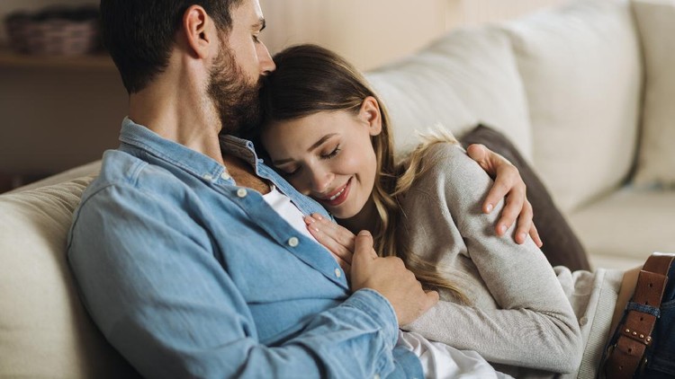 Young affectionate couple enjoying together while man is kissing his girlfriend in head