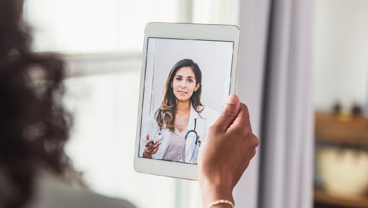 A female doctor offers an unrecognizable female patient advice during a telemedicine appointment.