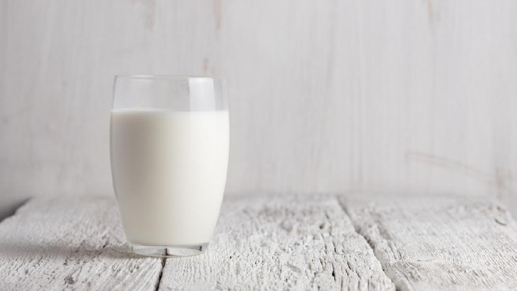 Glass of milk standing on old wooden table