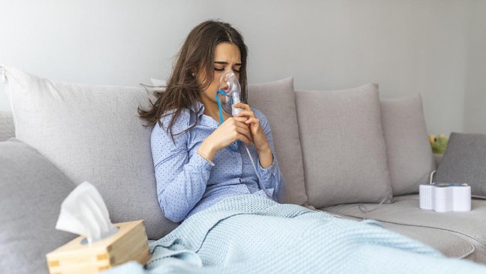 Woman holding a mask nebulizer inhaling fumes spray the medication into your lungs sick patient. Self-treatment of the respiratory tract using inhalation nebulizer