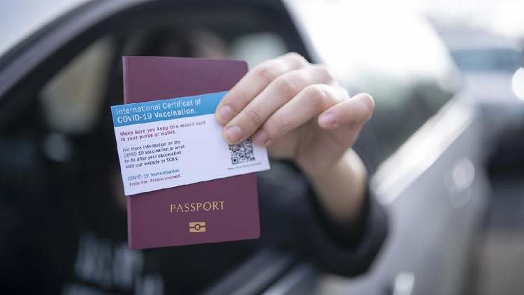 Unrecognisable person in car giving on border control passport and certificate of covid-19 vaccination.