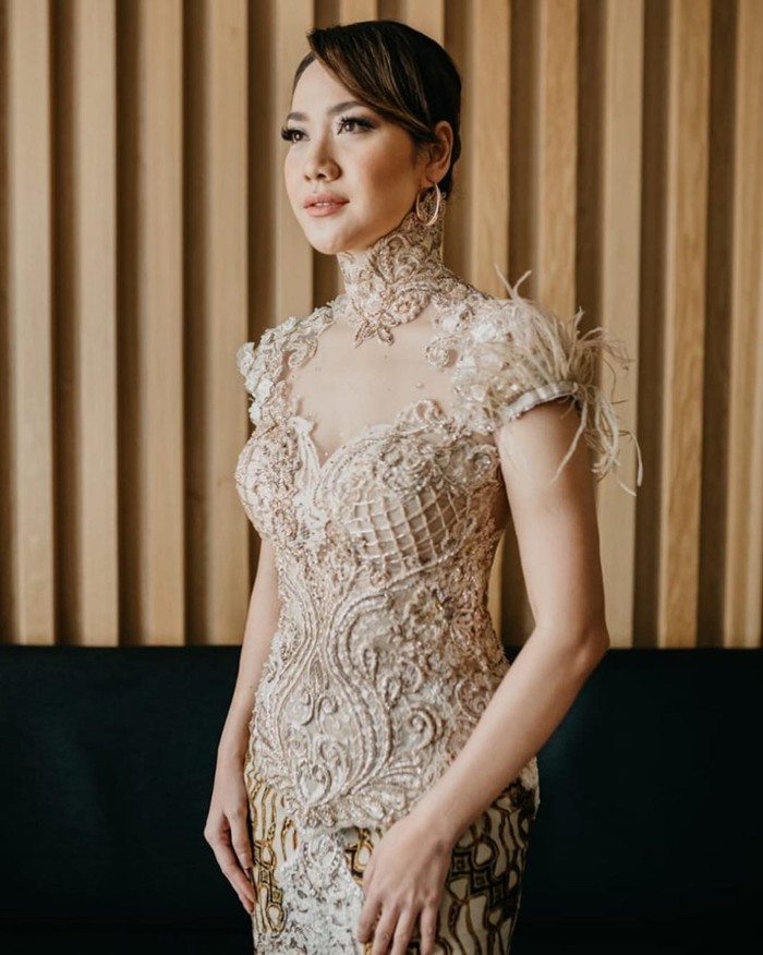 Kebaya warna nude ini membuat BCL terlihat anggun. Kerah tinggi dan hiasan bulu di lengan serta motif broklat timbul memberikan kesan glamor. Aksesoris yang minimalis membuat look ini jadi tidak berlebihan. (Foto: instagram.com/bclsinclair/panicartwork)