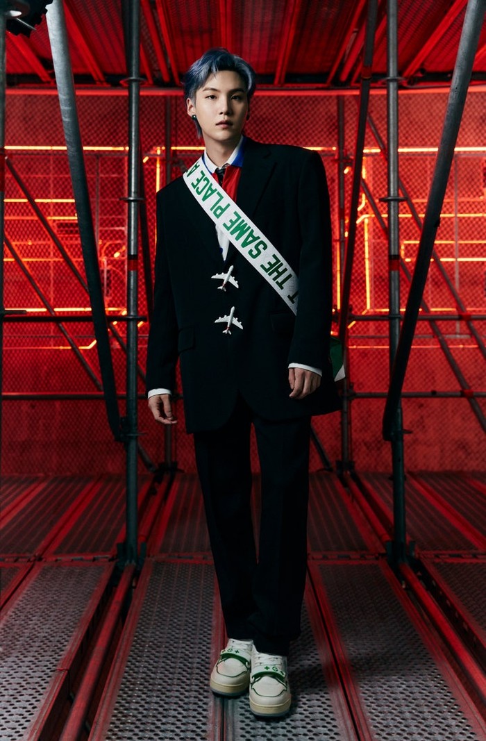 Tidak kalah dengan Kim Namjoon, Suga tampil memukau dengan setelan jas hitam dan tas slempang hijau. /Photos: Courtesy of Louis Vuitton/Instagram @voguejapan