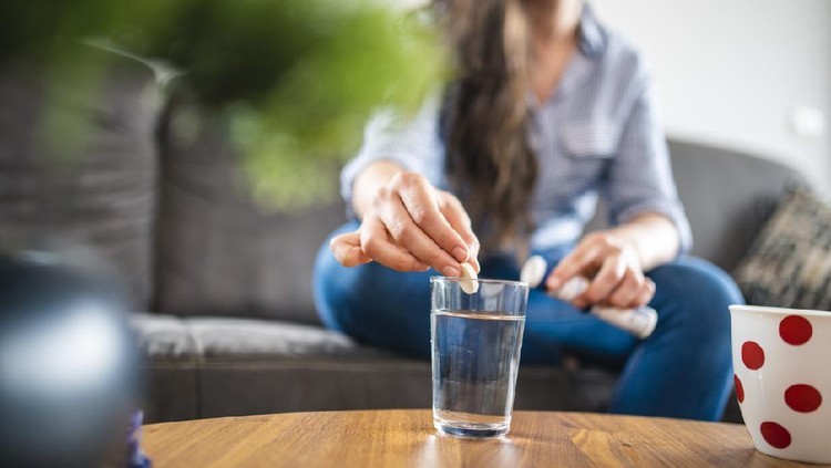 Ilustrasi Vitamin C Close up of a Caucasian Woman in her 20s dissolving a Effervescent Tablet in water